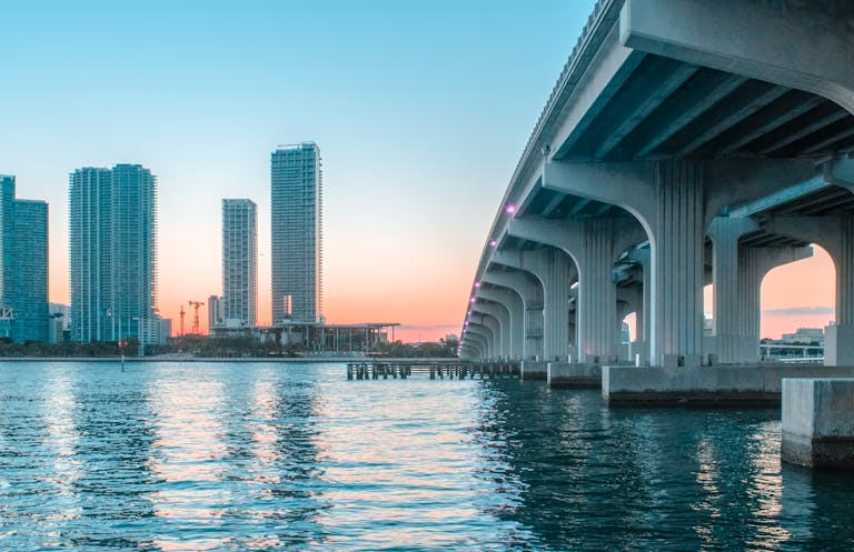 Stunning view of Miami Beach's skyline with a bridge at sunset, reflecting on the water.